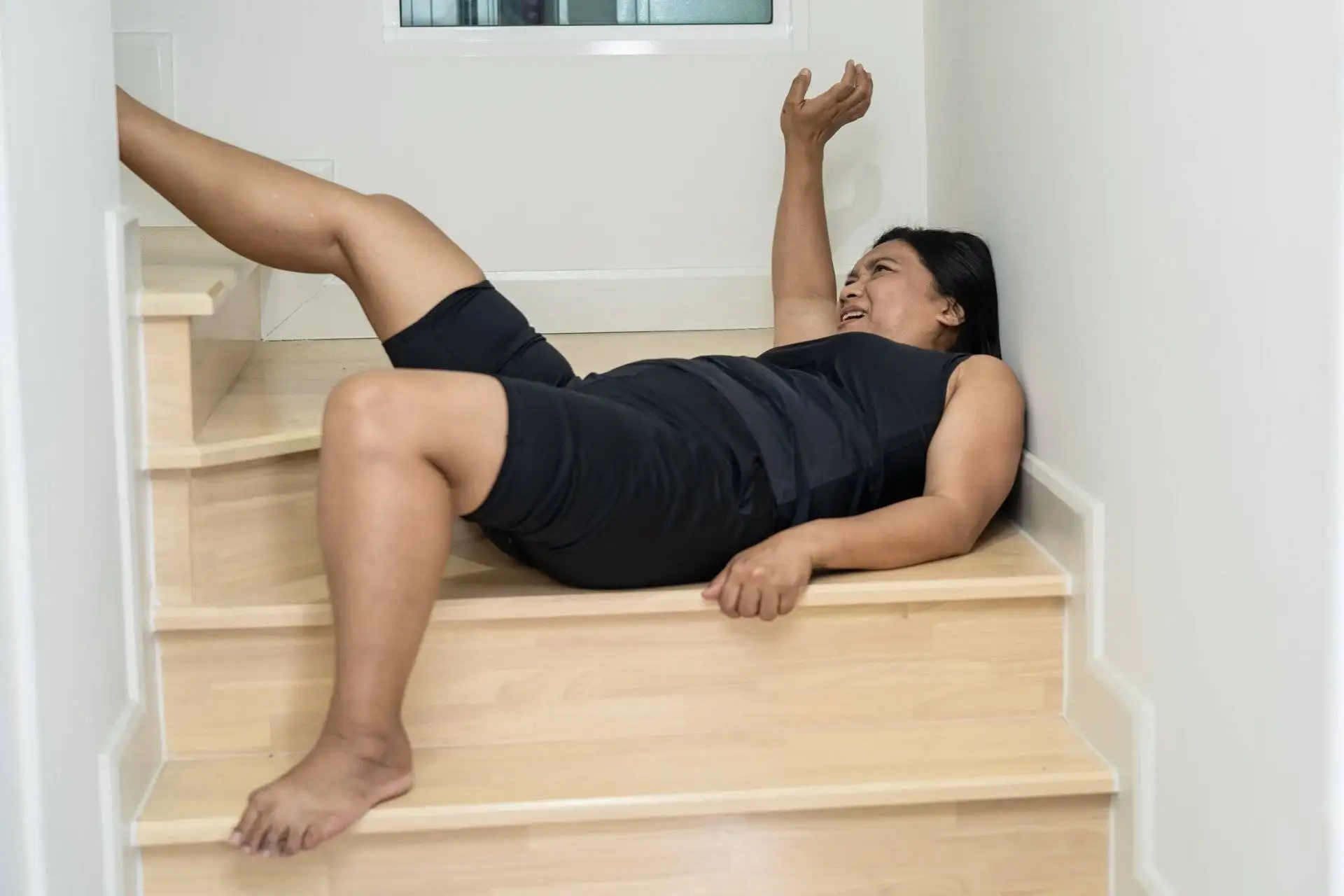 A middle-aged woman lies on the stairs in pain after a fall