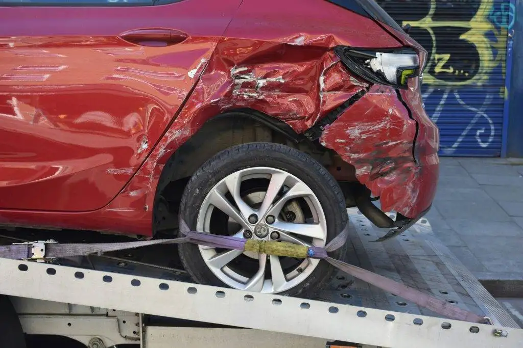 A red car with significant rear quarter panel damage