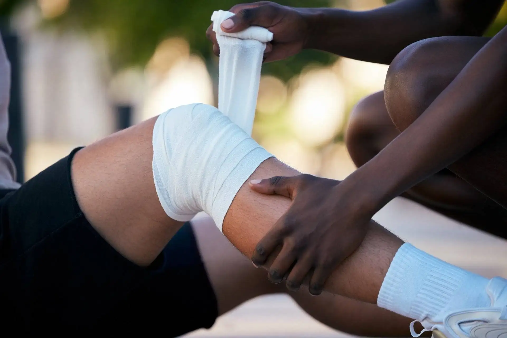 Athlete receiving first aid with knee wrapped in white bandage