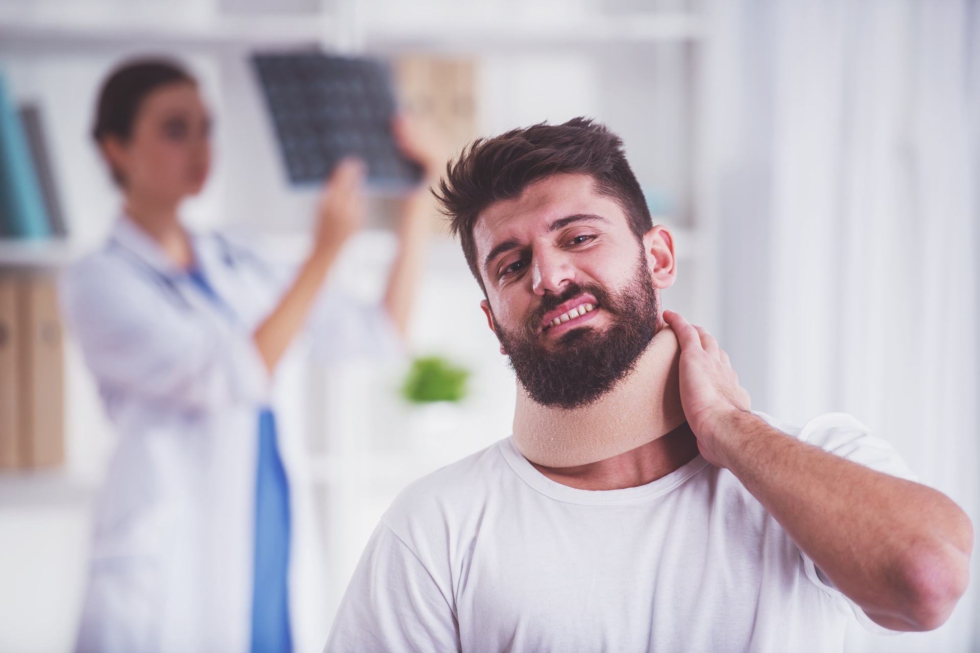 Injury neck. Young man with injured neck. Young woman doctor helps the patient