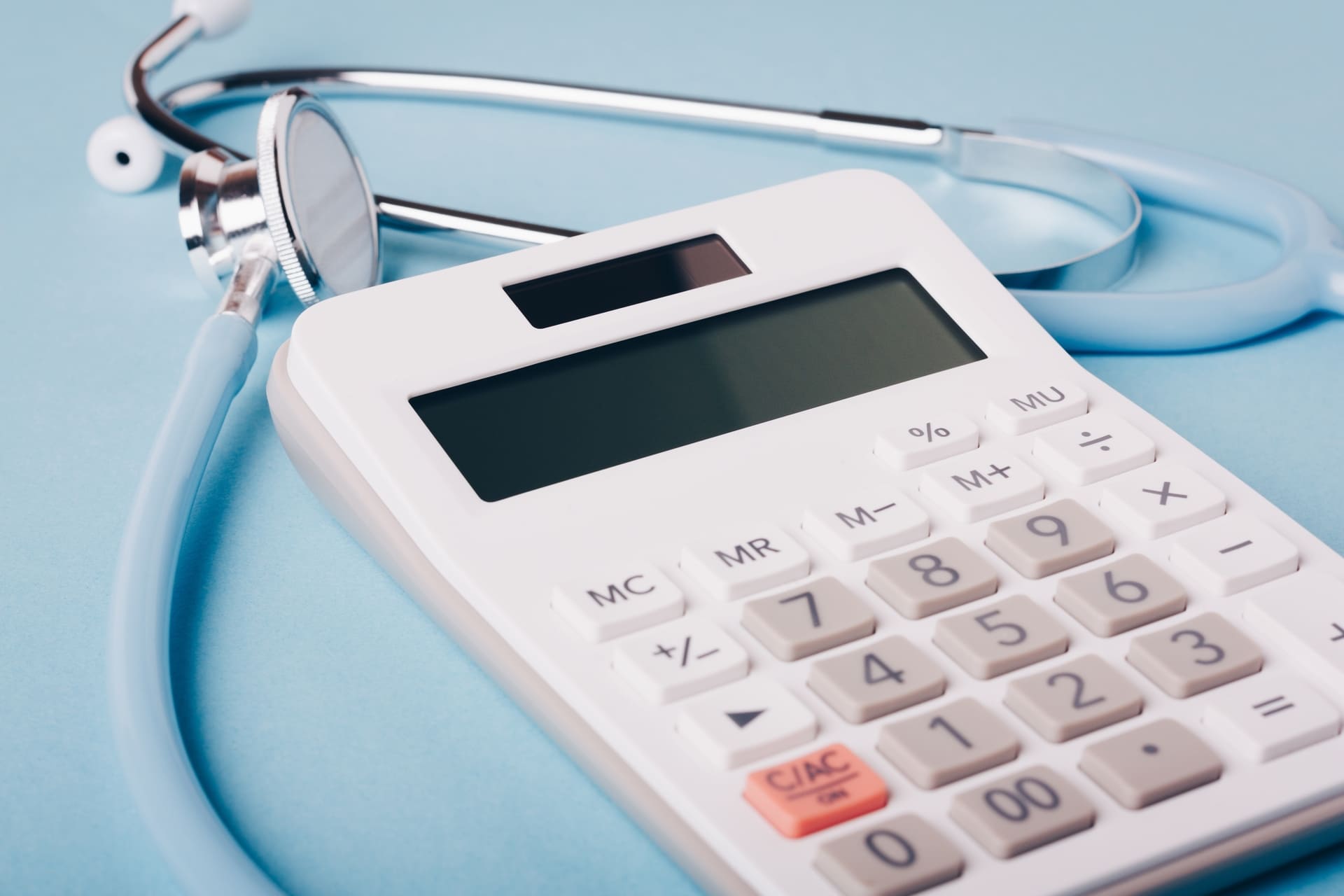 Calculator and stethoscope symbolizing healthcare cost calculation