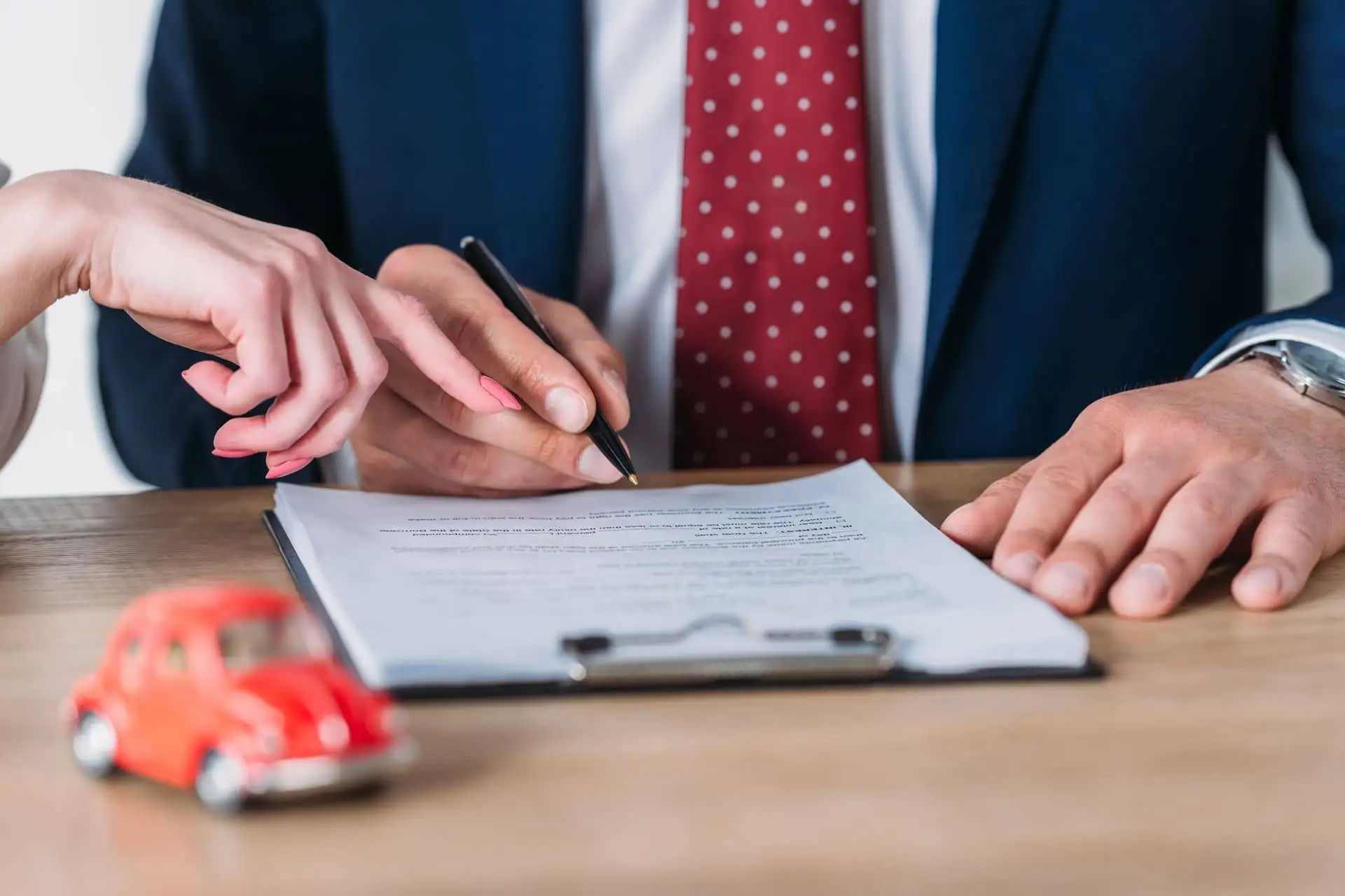 Close-up of a contract signing with a toy car in the foreground