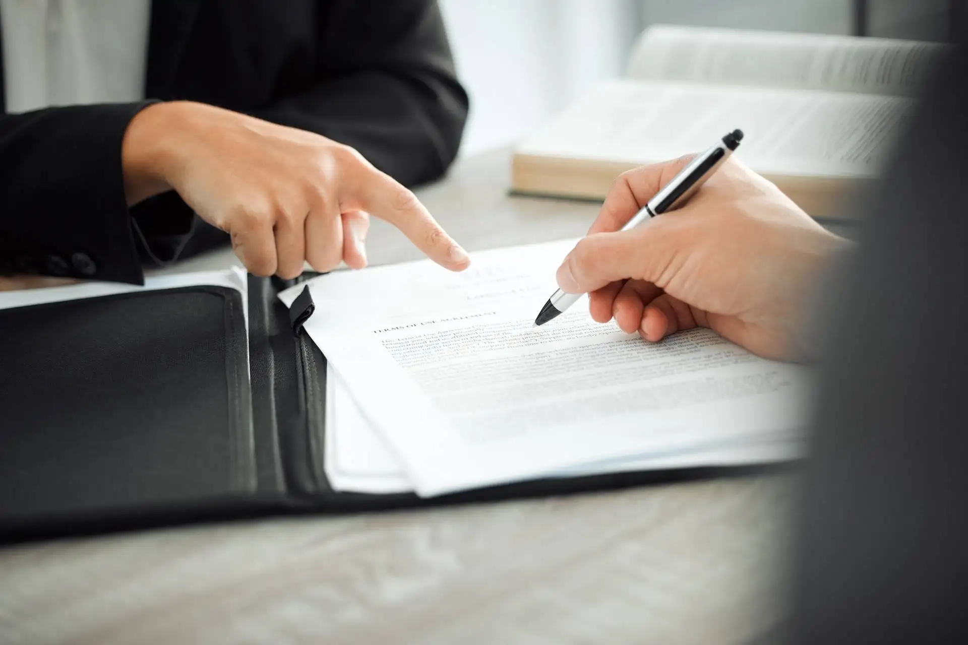 Close-up of two people reviewing and signing a legal contract