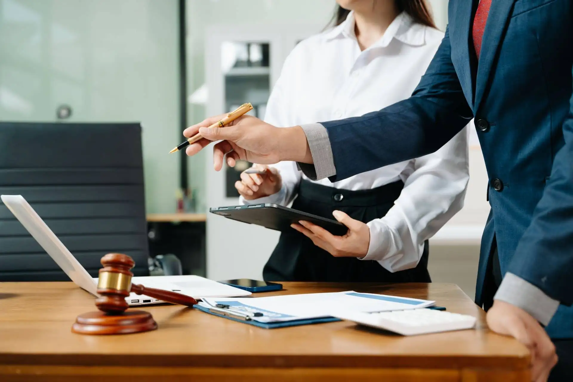 Close-up of two professionals reviewing legal documents on a desk with a gavel