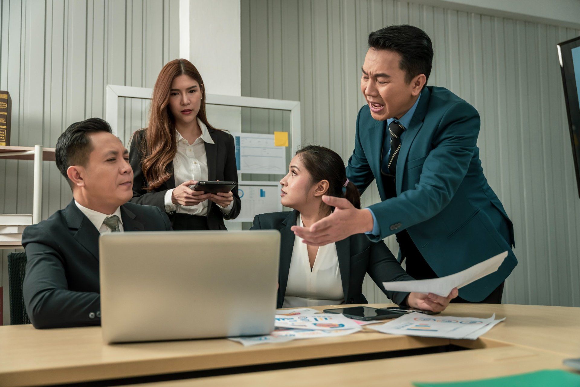 Colleagues blaming overwhelmed teammate at office desk