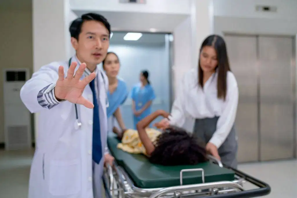 Doctor stopping with hand while patient on stretcher rushed by medical staff