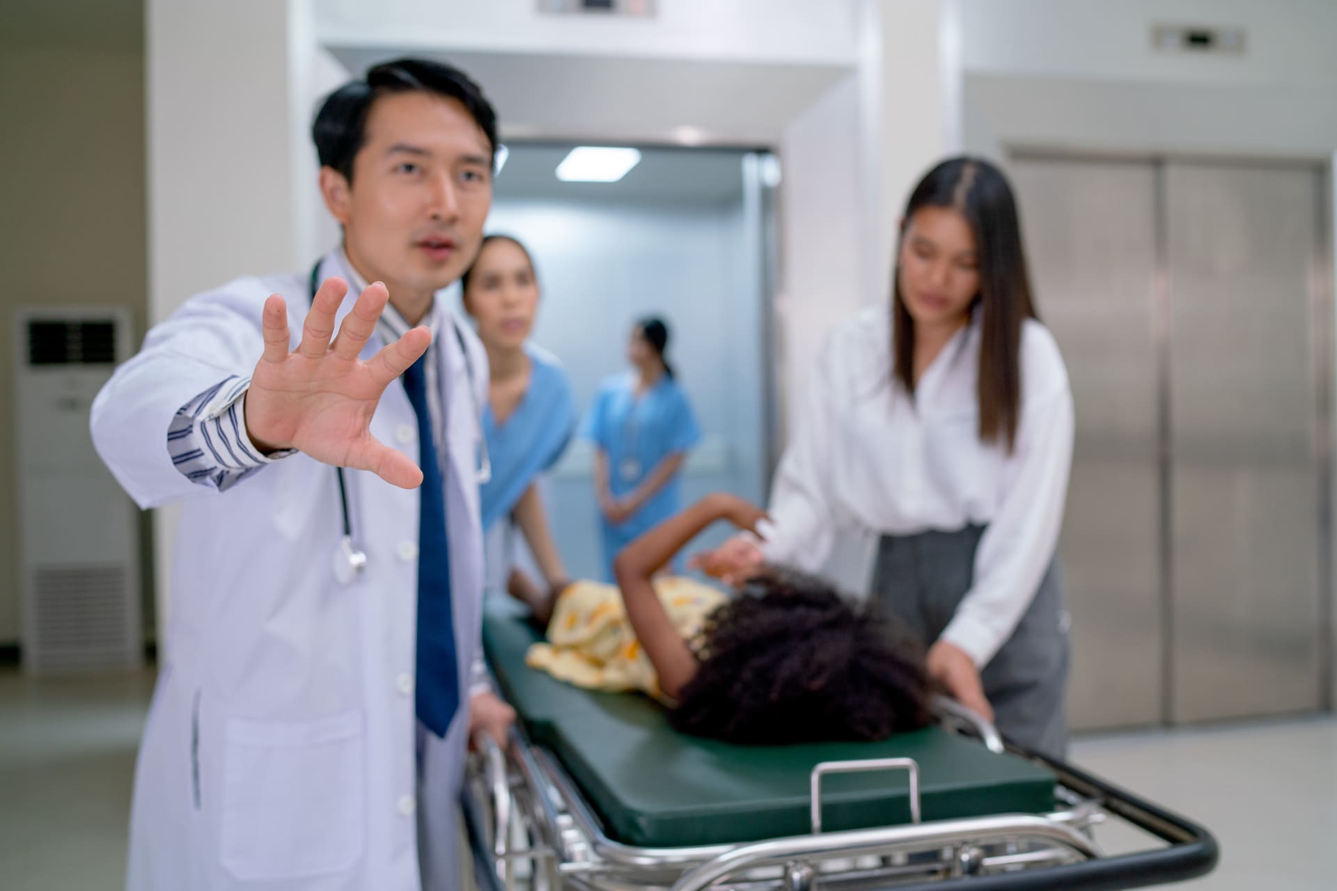 Doctor stopping with hand while patient on stretcher rushed by medical staff