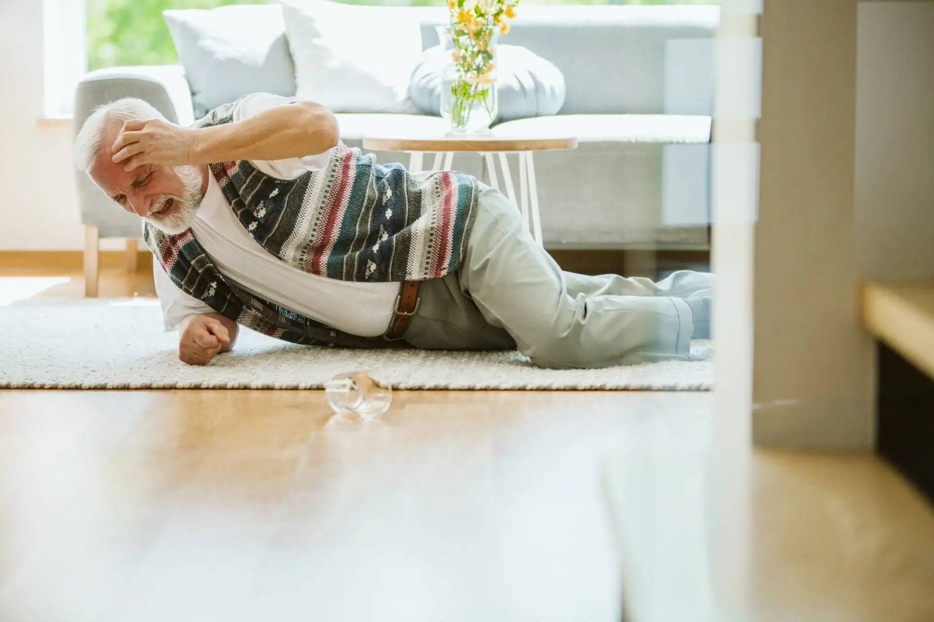 Elderly man in pain after falling at home near broken glass