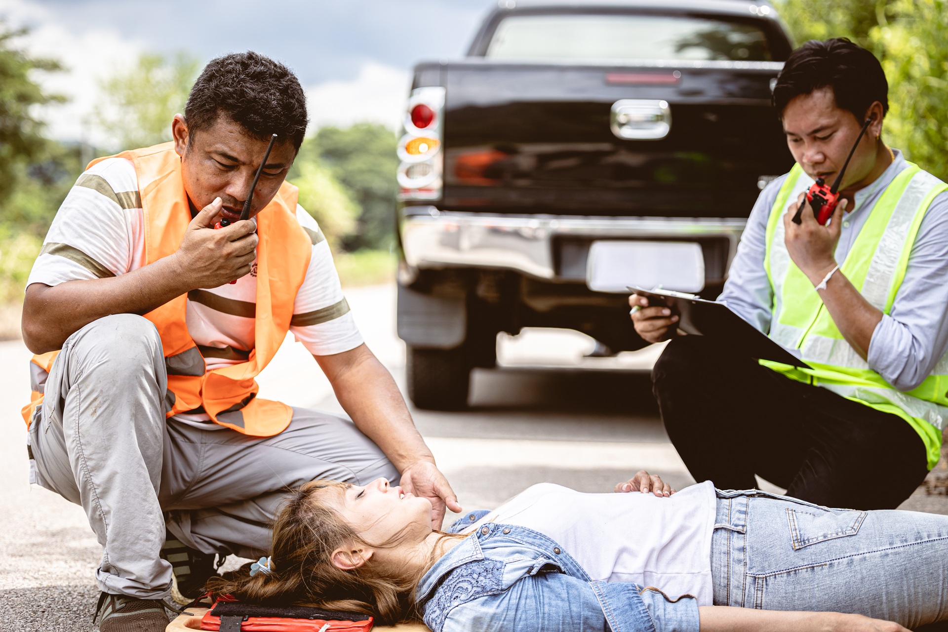 Emergency responders assisting an unconscious female accident victim on the road