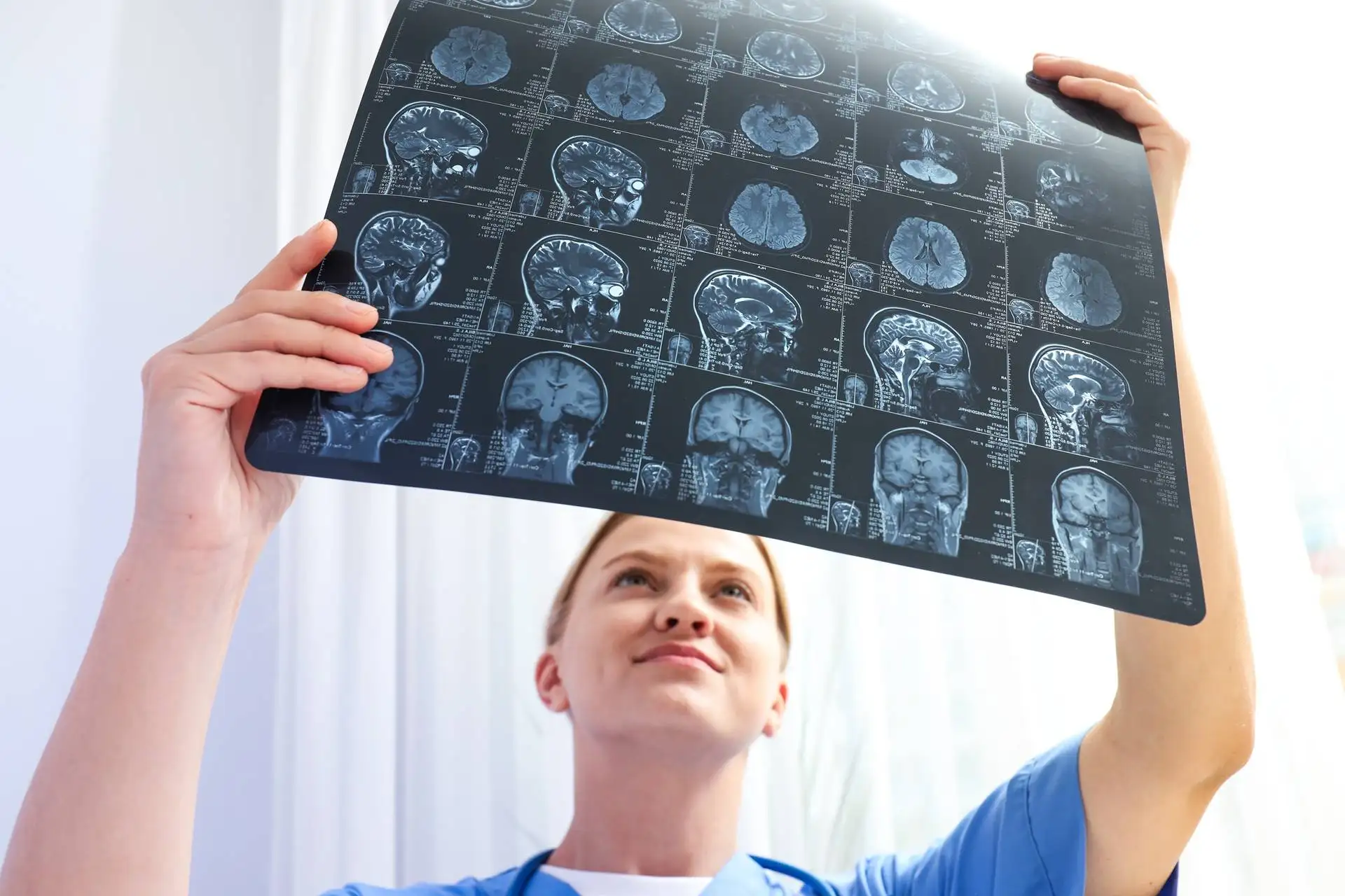 A young female doctor is looking at an MRI image of a human head