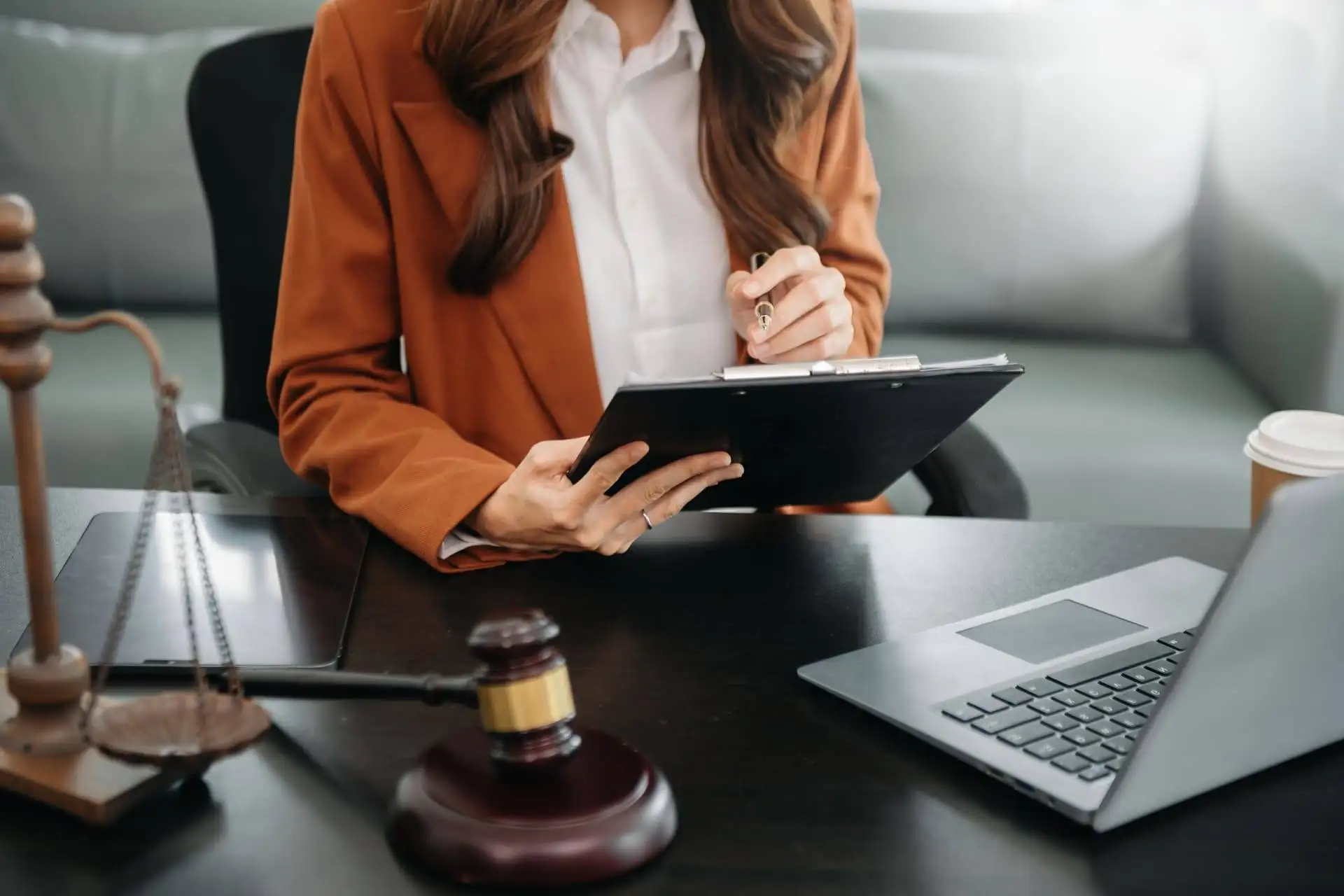 Female lawyer reviewing documents with scales of justice and gavel on desk