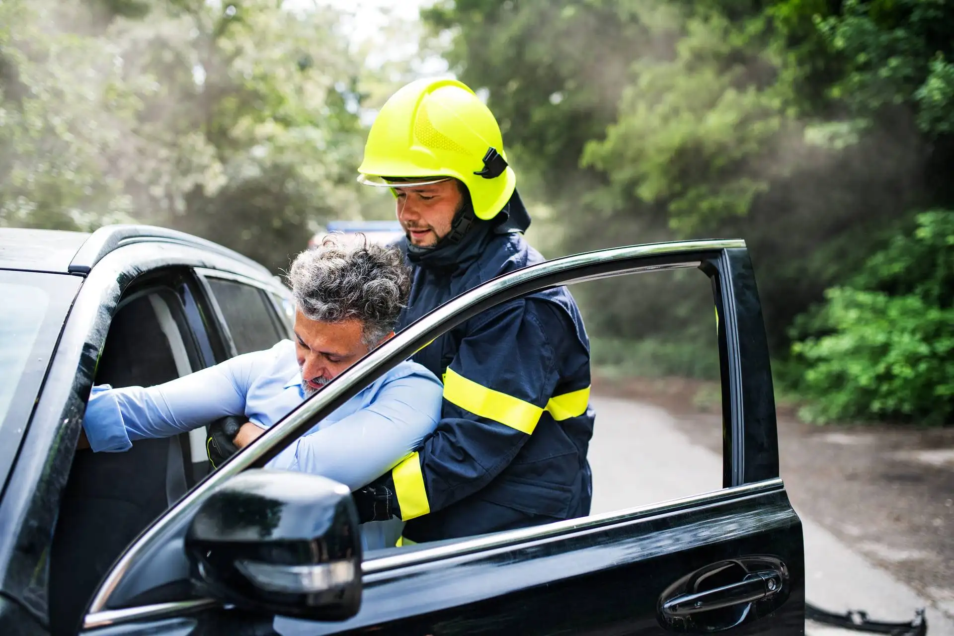 Firefighter rescuing an unconscious man from a car