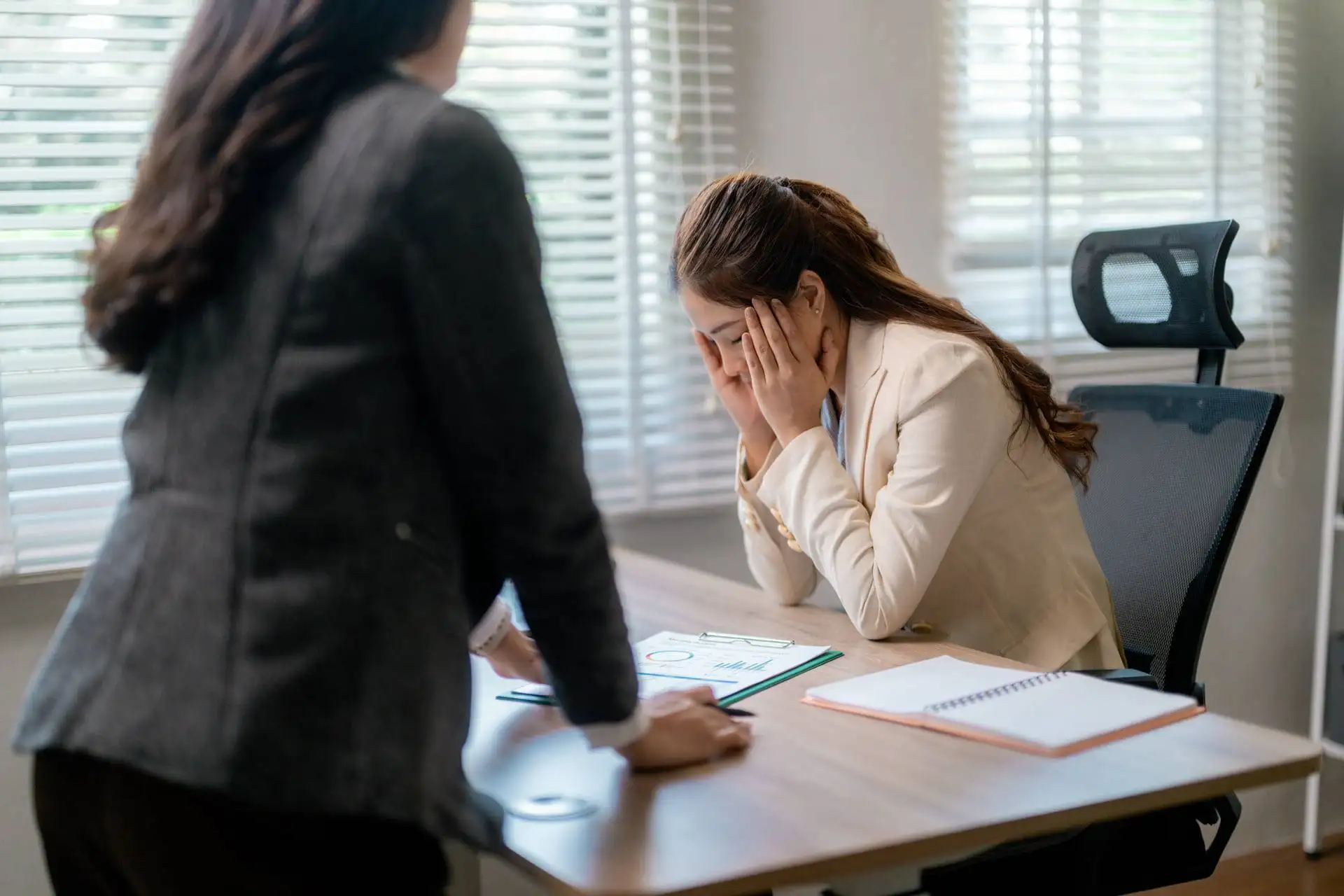 Frustrated businesswoman holding her face during a tense office discussion