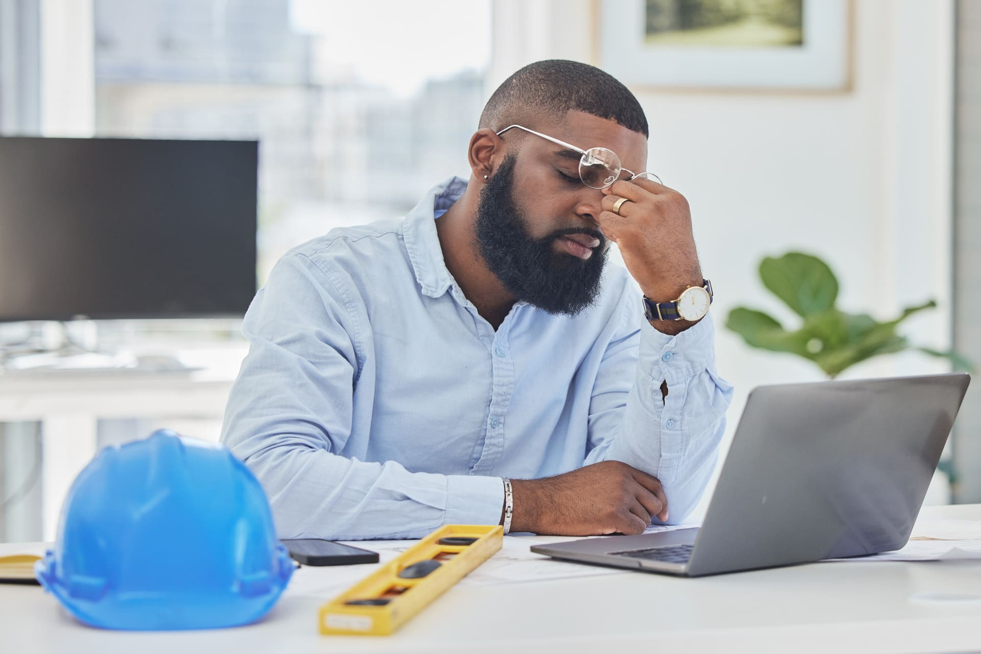 Frustrated engineer with a laptop, holding his forehead