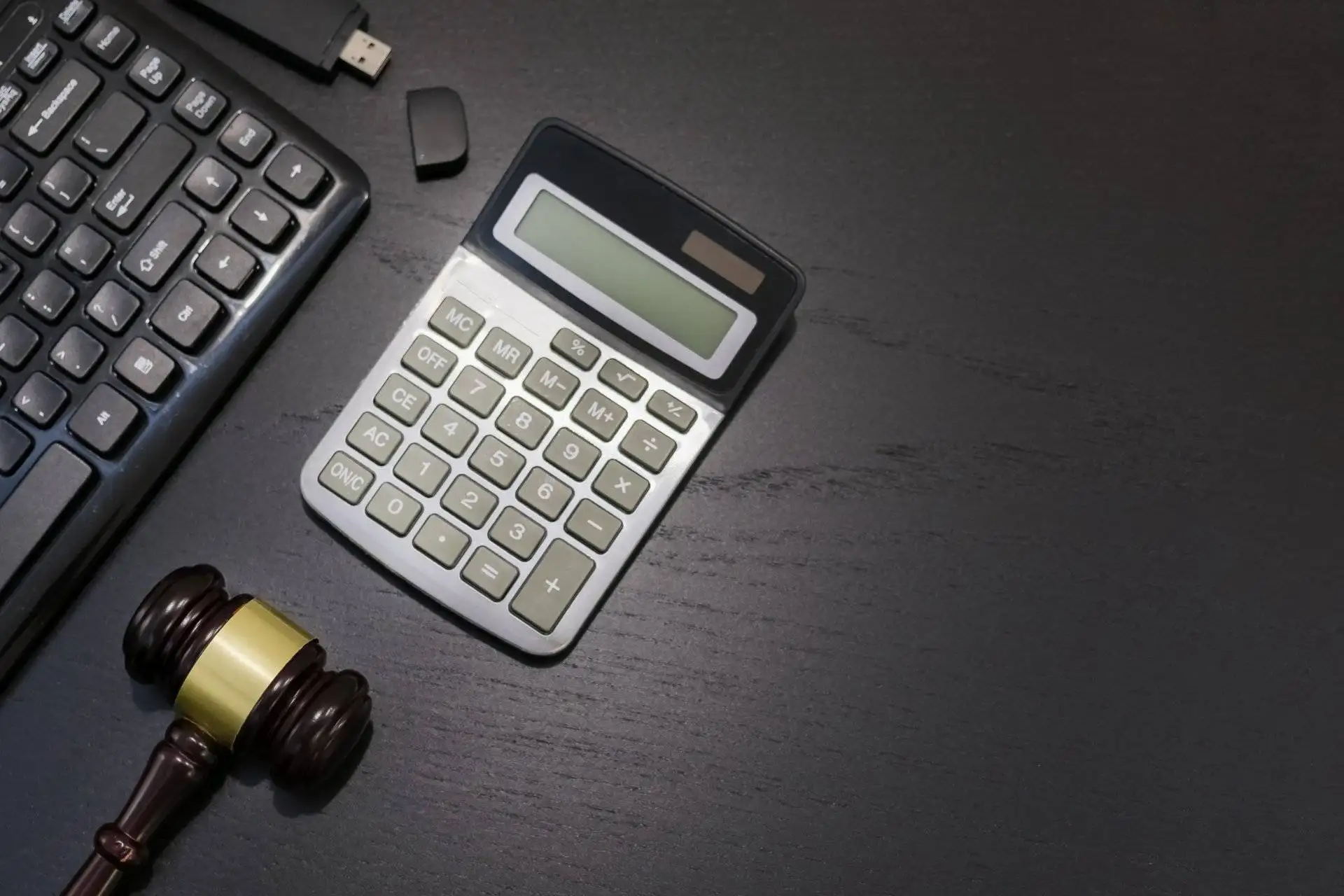 Gavel and calculator on lawyer’s desk with computer keyboard