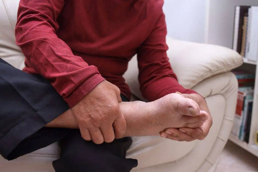 a man sat down holding the side of his foot
