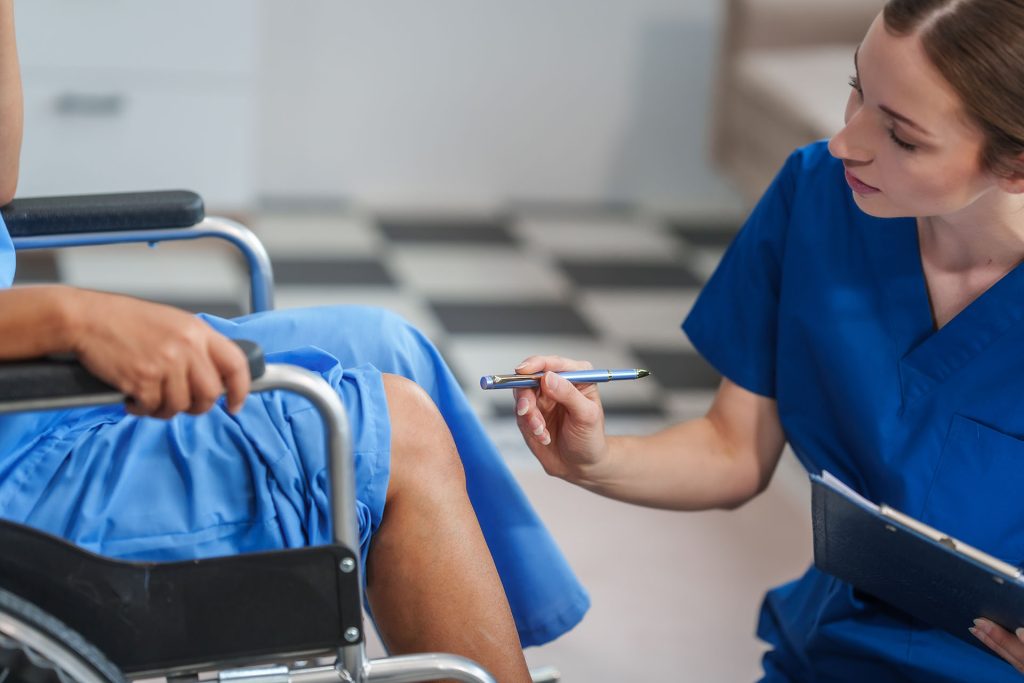 nurse testing a patient's nerve reactions in a wheelchair