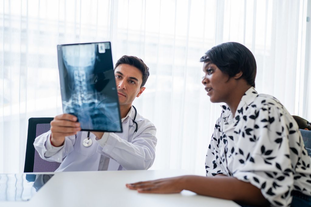 doctor holding up a spine x-ray to a patient