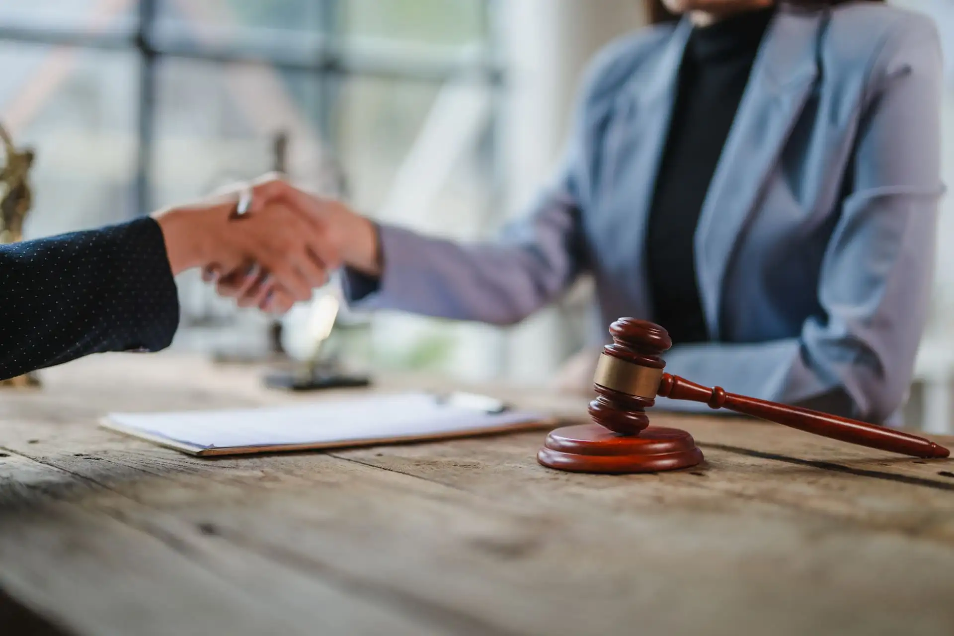 Lawyers shaking hands after signing a legal agreement with gavel on table