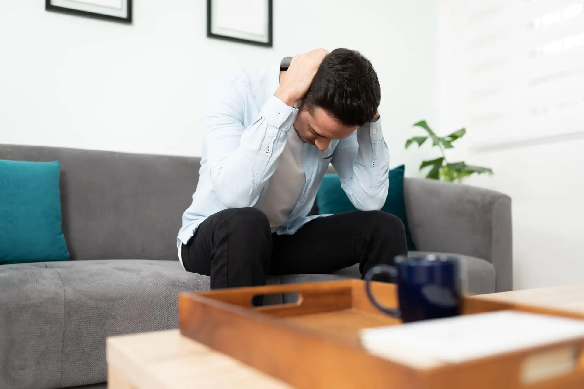 Man sitting on a couch holding his head in frustration