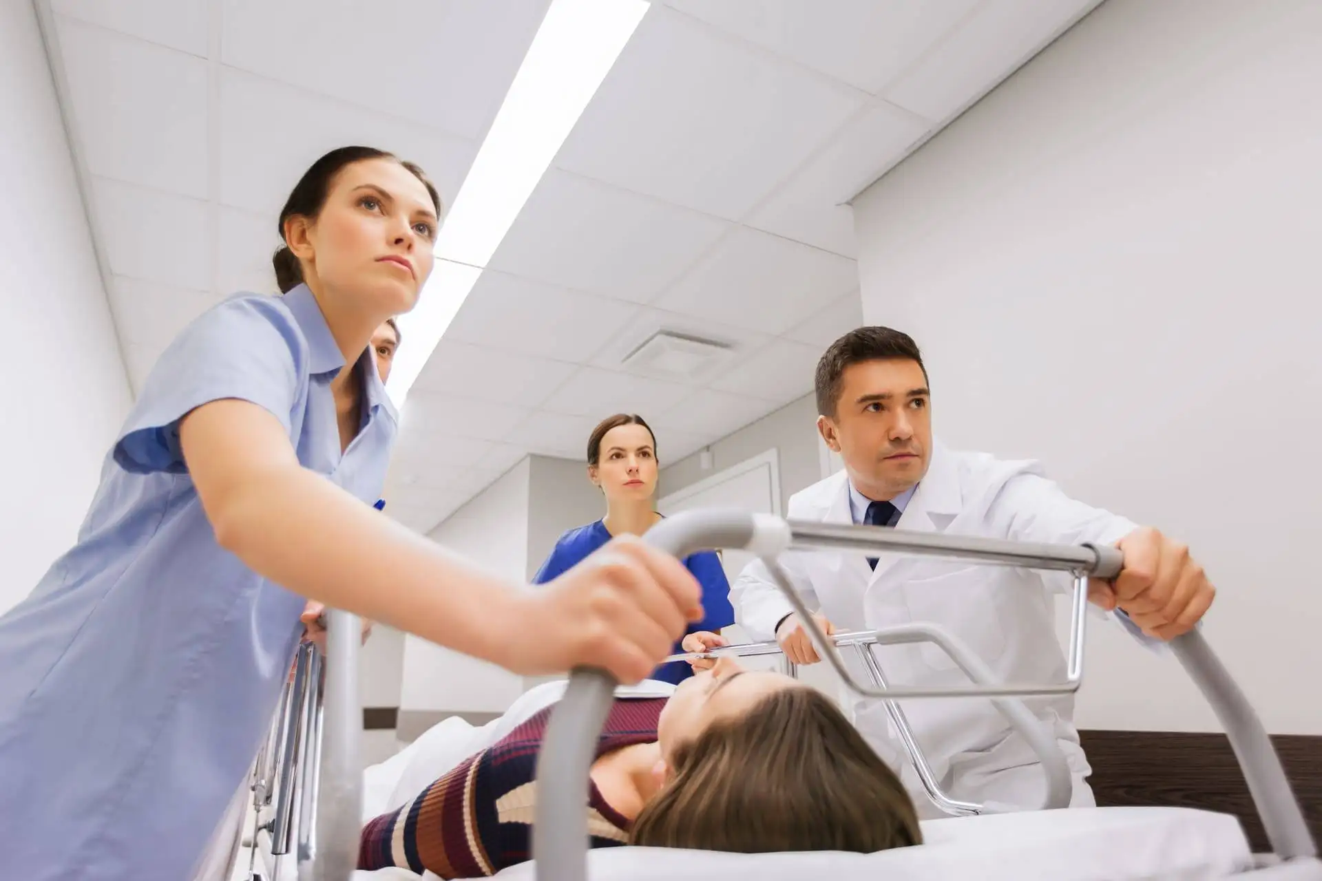 Medical team rushing patient on stretcher through hospital corridor