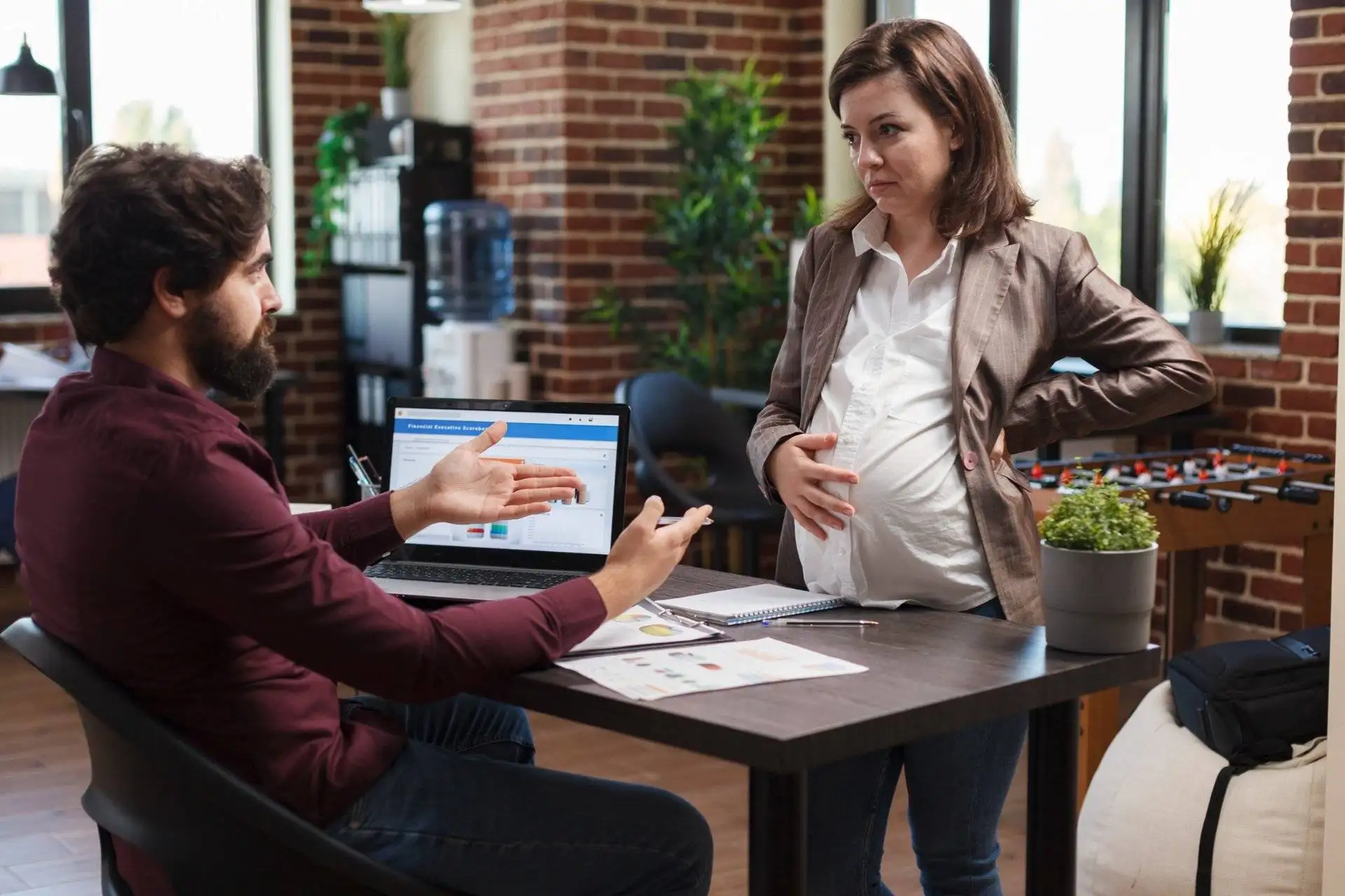 Pregnant employee having a conversation with her colleague in the office