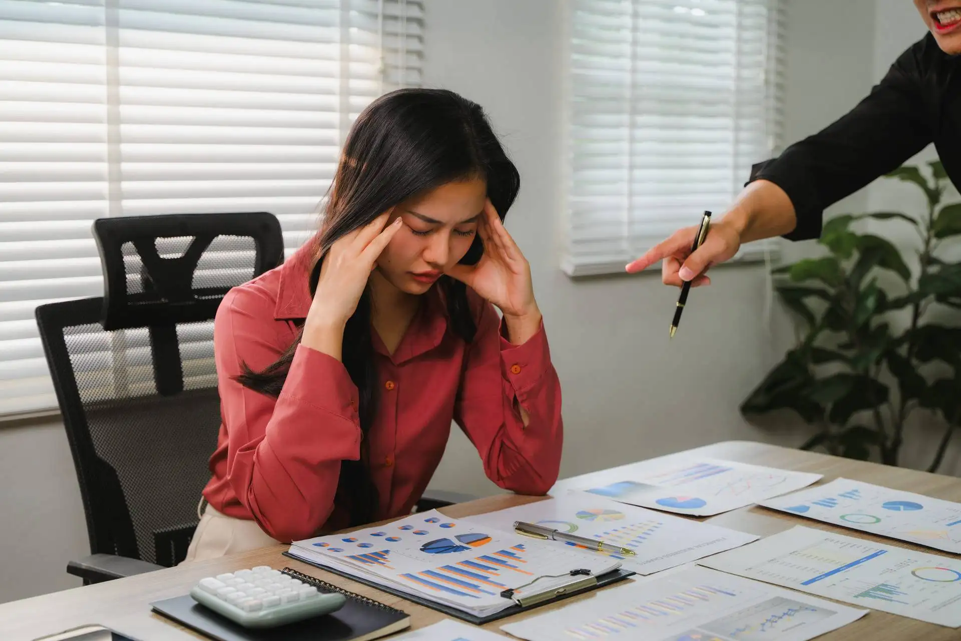 Stressed employee being scolded by a manager during a meeting