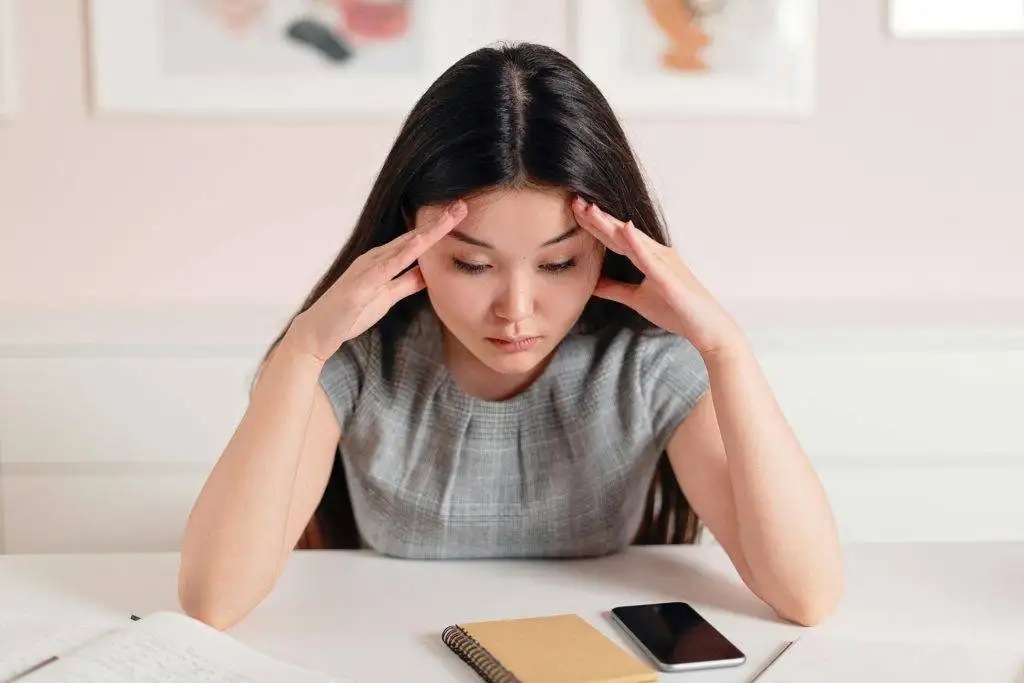 Stressed woman with hands on her head at desk