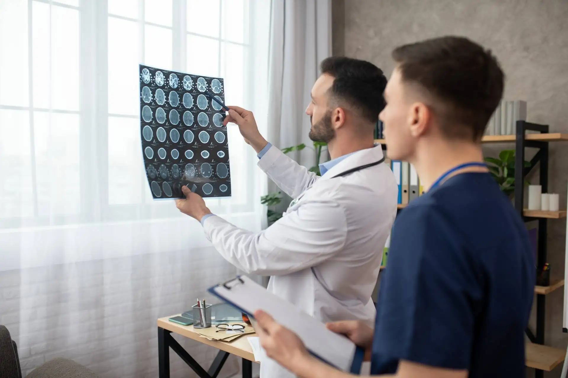 Bearded young doctor and his colleague looking involved while analyzing MRI results