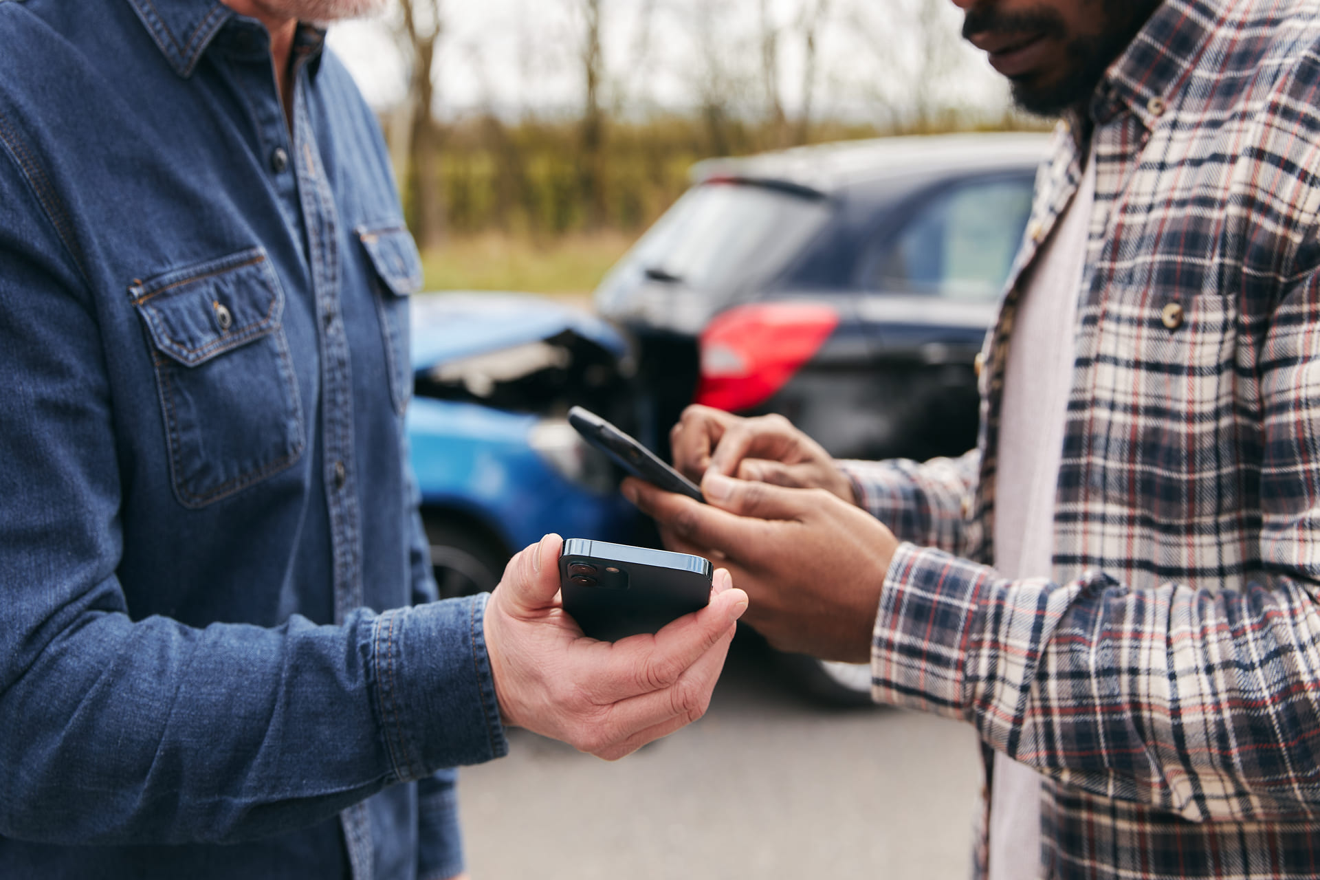 Two men exchanging insurance details after a car crash