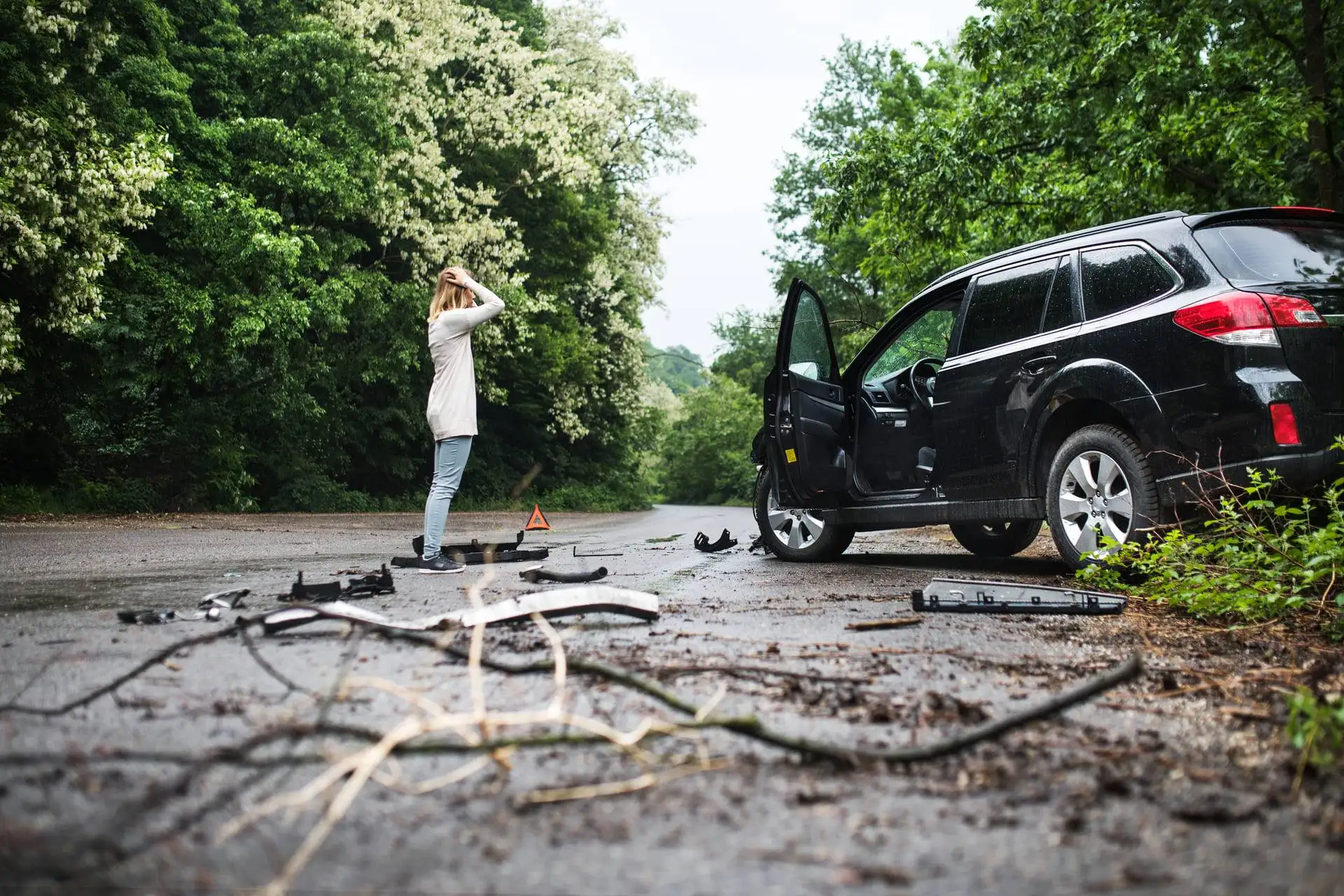 Woman standing near a damaged vehicle after an accident