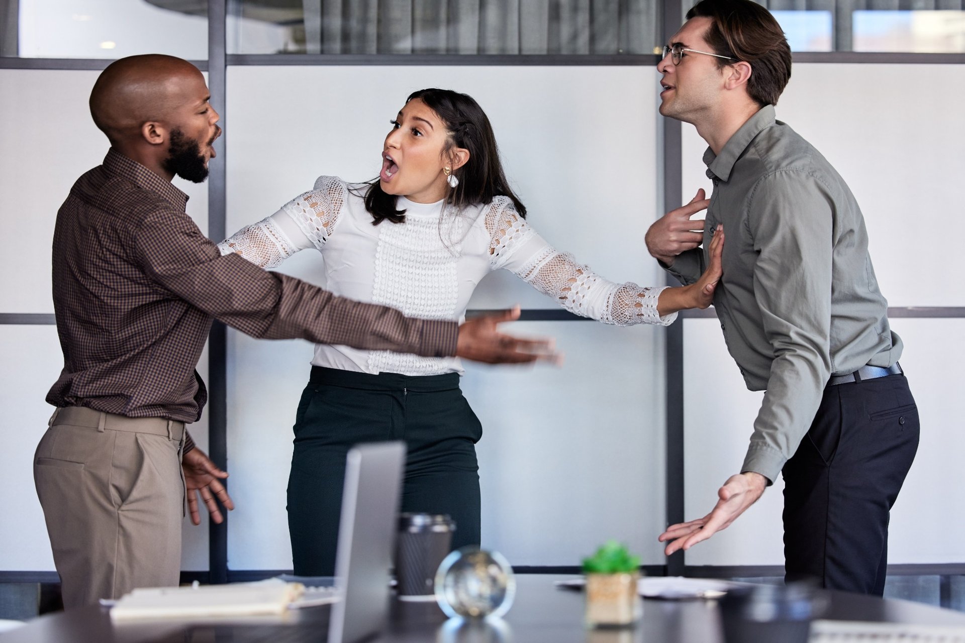Woman trying to stop a heated argument between two men in office