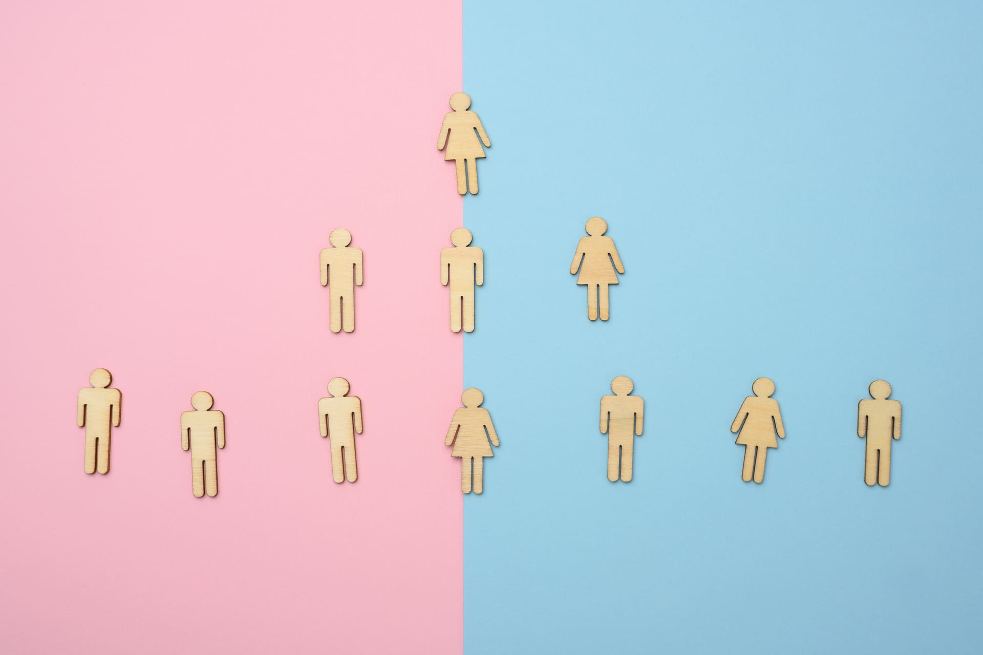 Wooden male and female icons arranged on pink and blue background