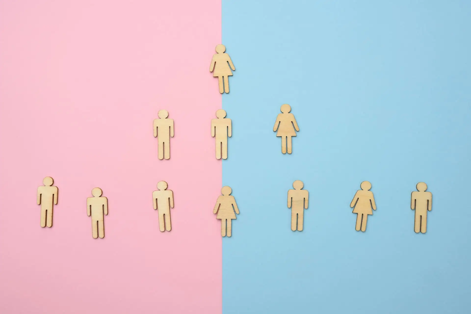 Wooden male and female icons arranged on pink and blue background