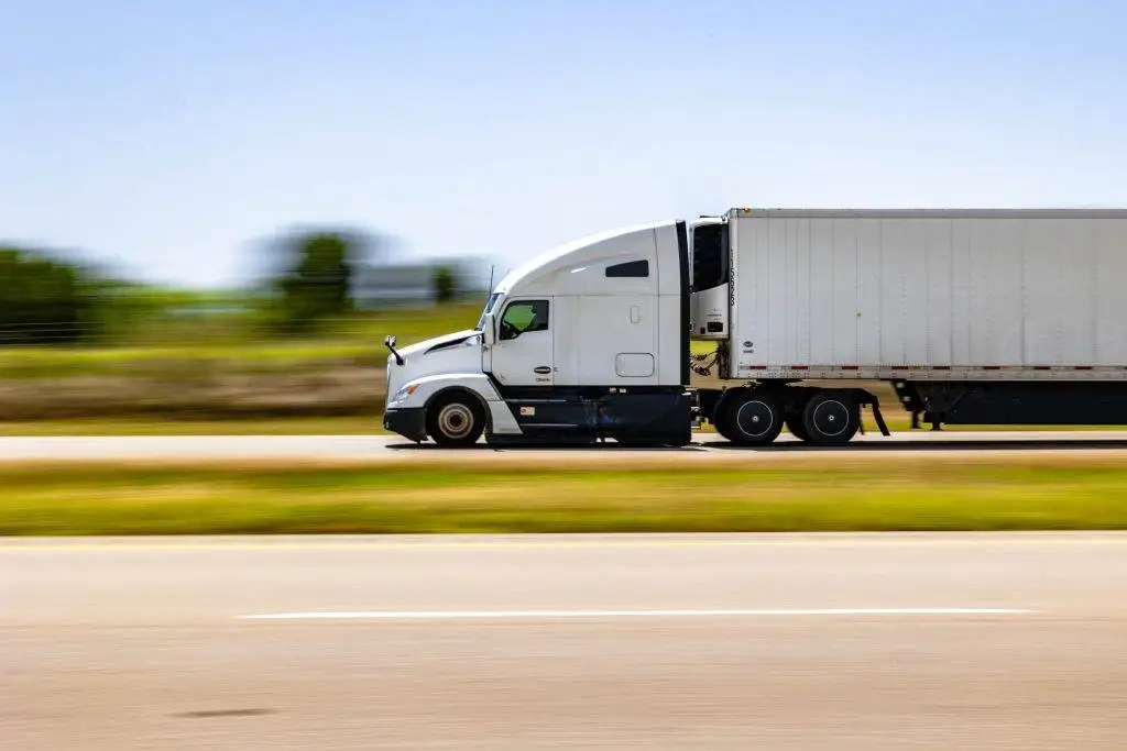 a semi truck moving along a rural road