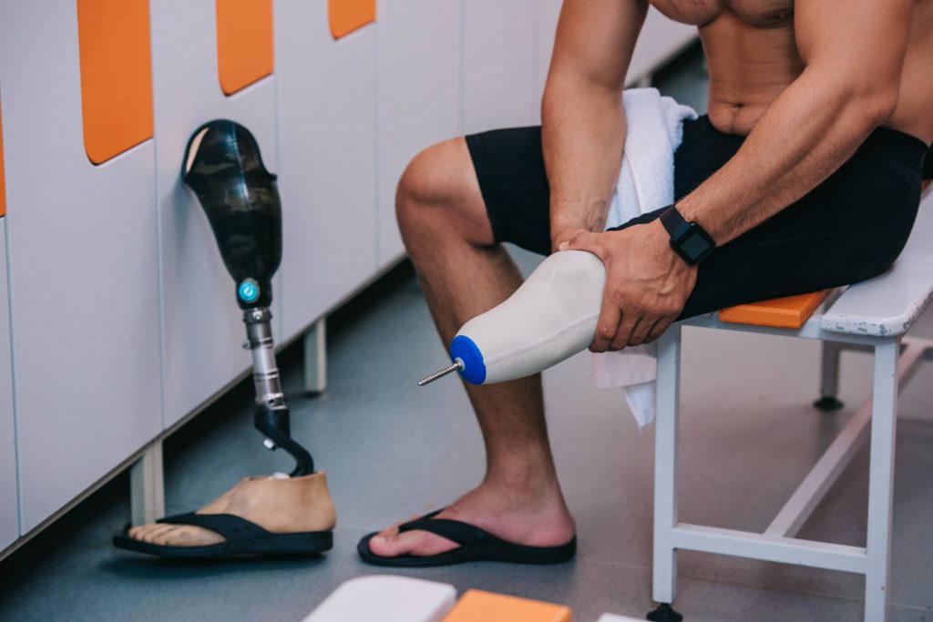 athletic male in a changing room fitting his left lower prosthetic leg