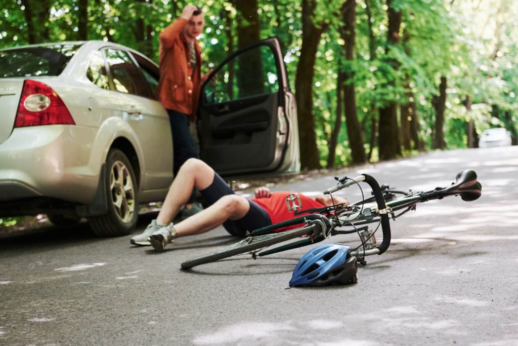 bicycle victim lying on a road with a car behind