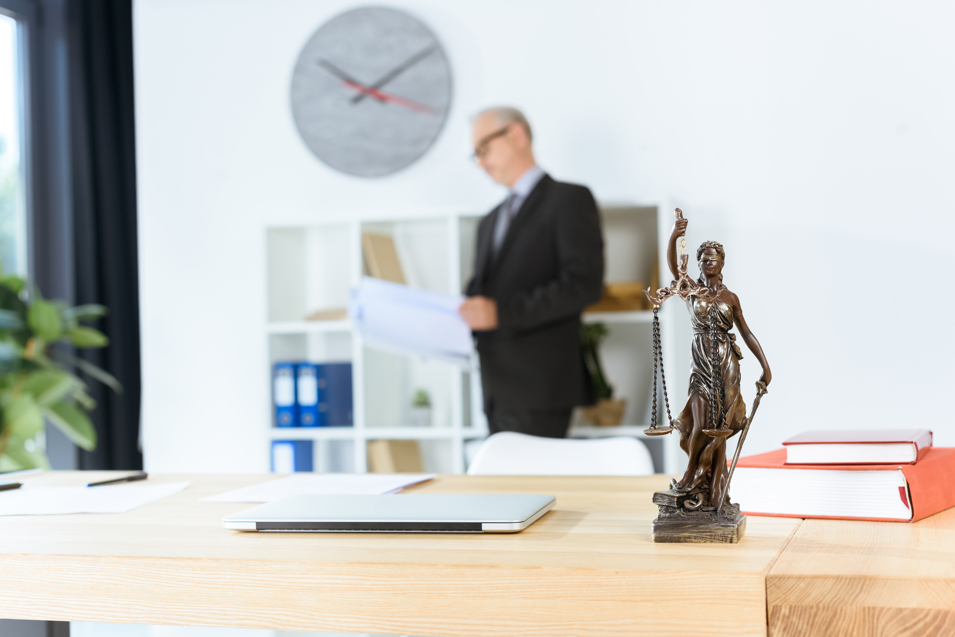 femida sculpture on table with blurred mature lawyer
