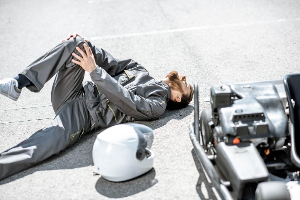 motorcycle rider lying on the ground holding his knee