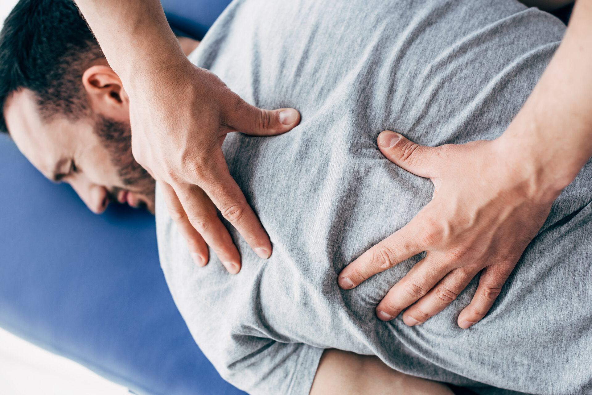 physiotherapist massaging back of man lying