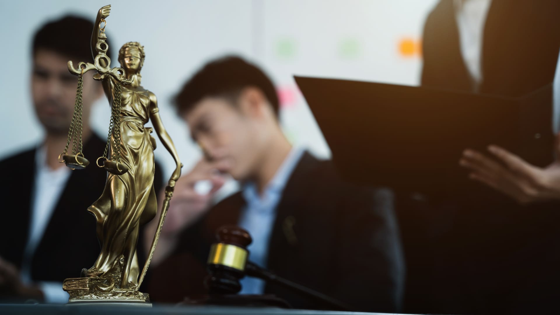 Statue of lady justice with lawyers in the background