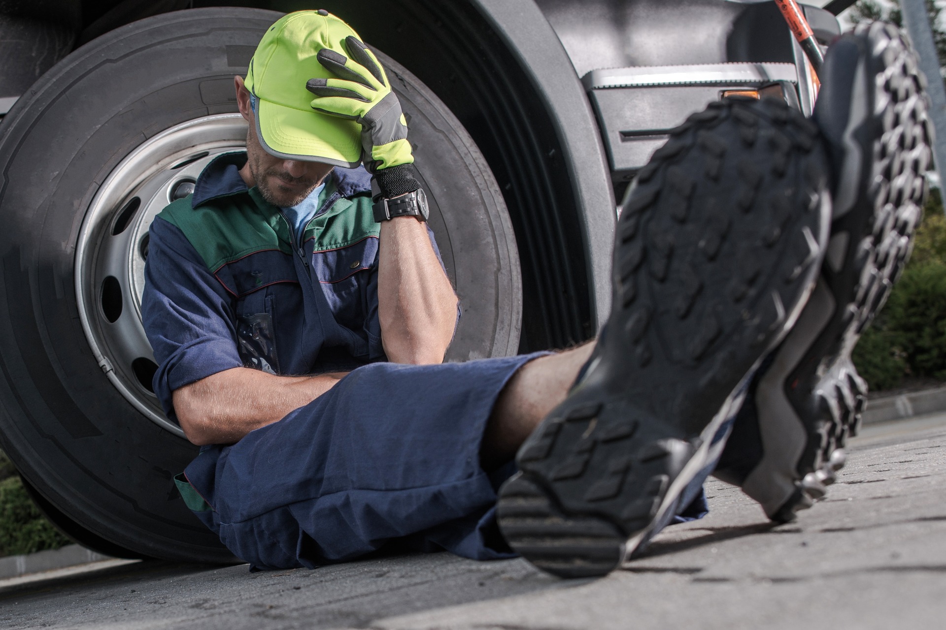 the driver sits leaning on the truck wheel