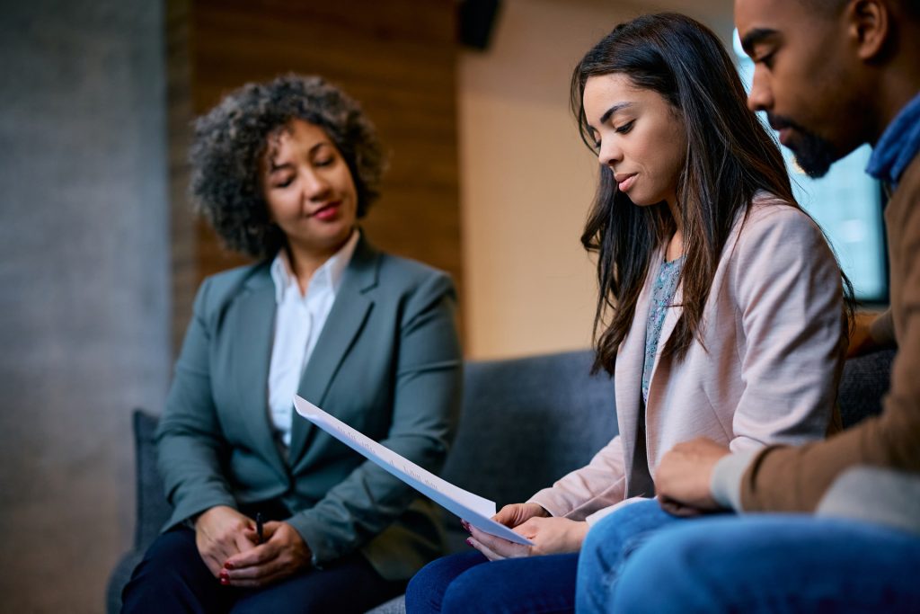 young couple reading document with lawyer