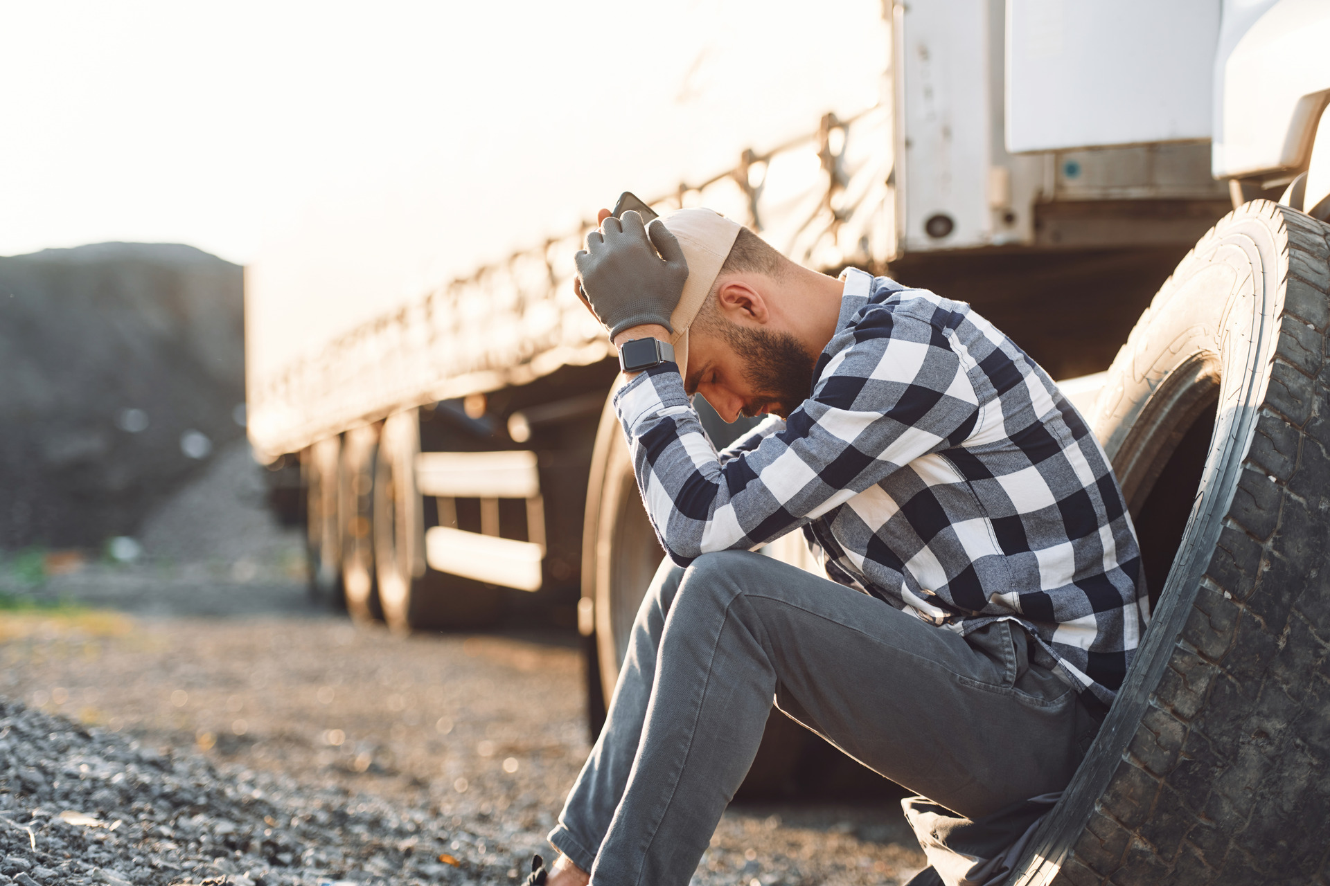 young truck driver sitting on tire